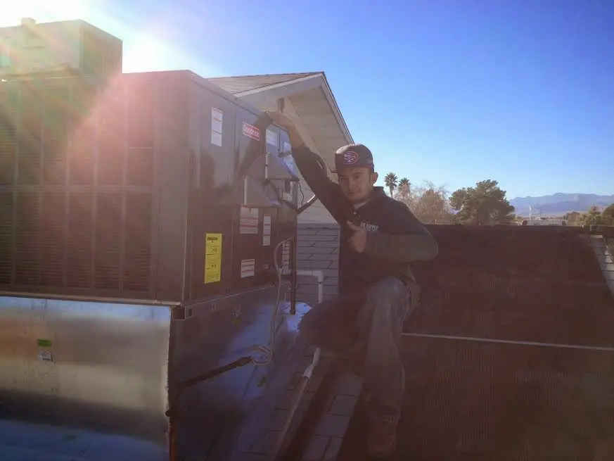 HVAC technician performing Boiler Repair on a rooftop unit in August